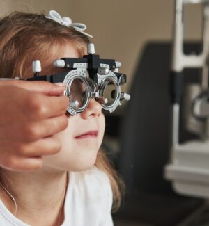 Health care of the eyes. Doctor checking little girl sight and tuning the phoropter